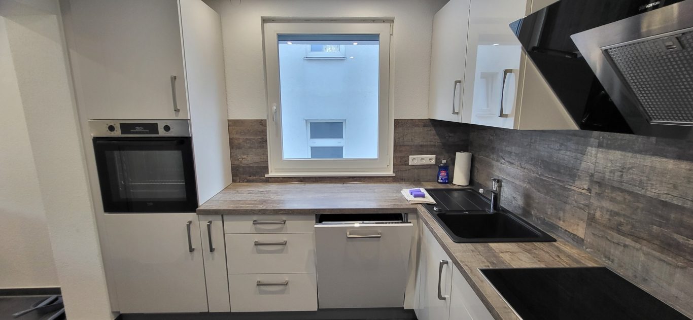 Moderne Küche mit weißem Design, Holzdetails und Geräten wie Herd und Ofen. Moderne Küche mit weißem Design, Holzdetails und Geräten wie Herd und Ofen.