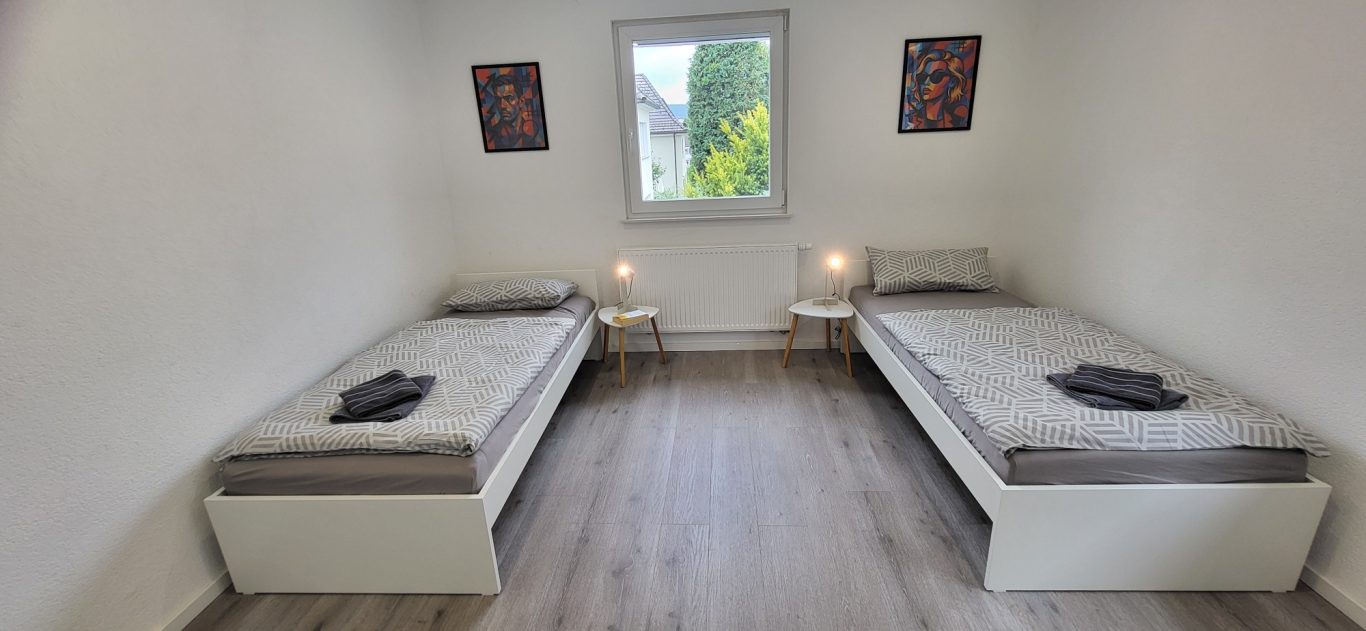 Zwei Einzelbetten in einem hellen, minimalistisch eingerichteten Raum. Zwei Einzelbetten in einem hellen, minimalistisch eingerichteten Raum.