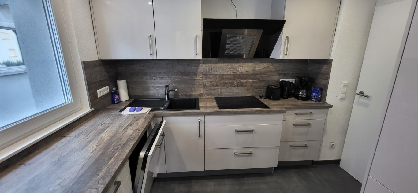 Moderne Küche mit Holzdetails, Elektrogeräten und Fenster für Tageslicht. Moderne Küche mit Holzdetails, Elektrogeräten und Fenster für Tageslicht.