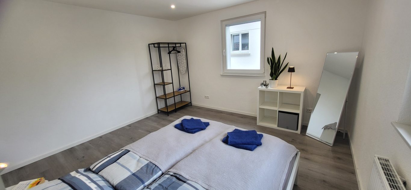 Helles Schlafzimmer mit zwei Betten, Handtüchern, Regal und großem Spiegel. Helles Schlafzimmer mit zwei Betten, Handtüchern, Regal und großem Spiegel.