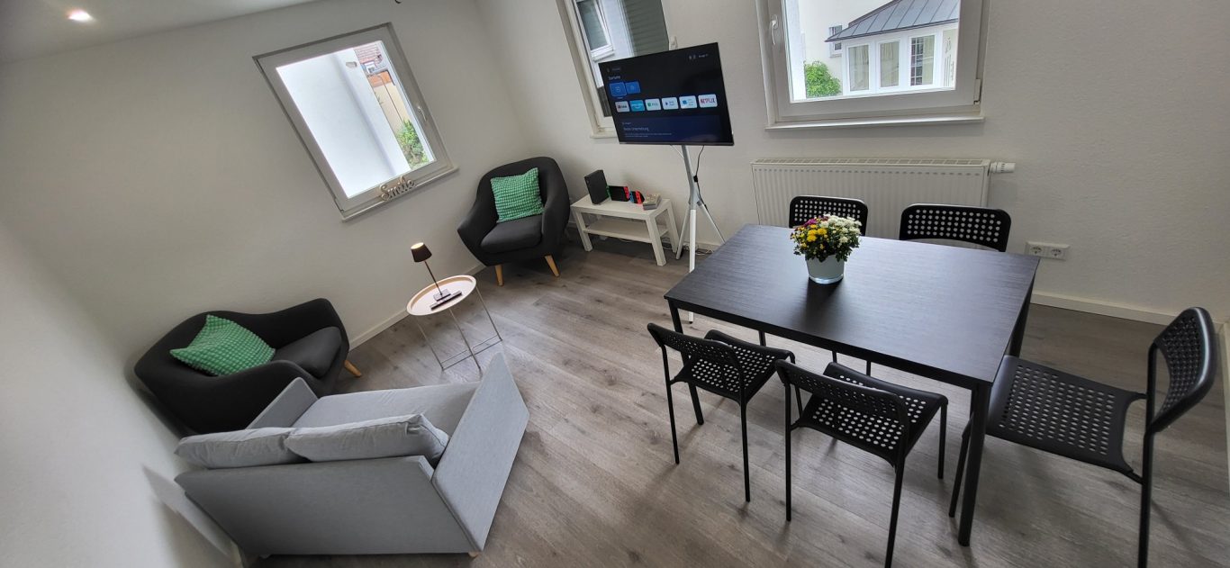 Moderne Wohnküche mit Tisch, Stühlen, Sofas und einem Fernseher. Helle Farben und Fenster. Moderne Wohnküche mit Tisch, Stühlen, Sofas und einem Fernseher. Helle Farben und Fenster.